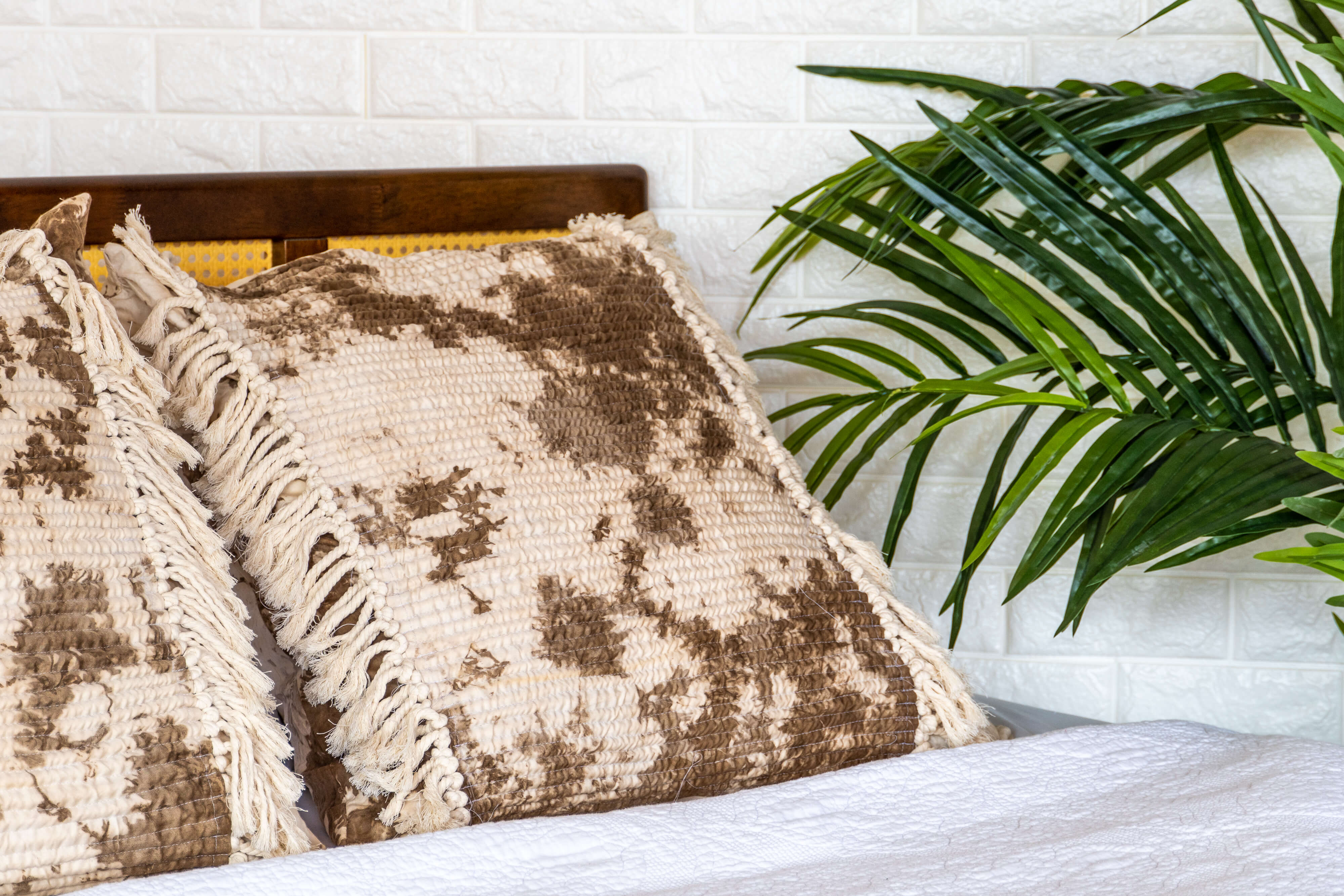 Walnut Flora Fringe Pillows on a bed